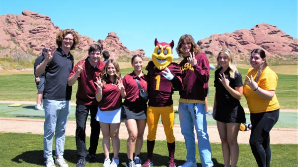 ASU Sparky mascot posing with students on golf course
